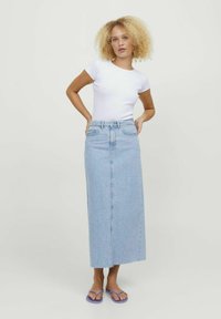 Light blue denim maxi skirt with a straight cut, high waist, and frayed hem. Paired with a fitted white t-shirt and purple flip-flops.