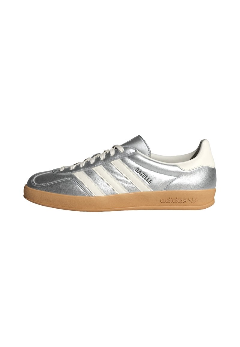 Silver Adidas Gazelle-sneaker med vita ränder, gummisula och "Gazelle"-text på sidan, visad från insidan.
