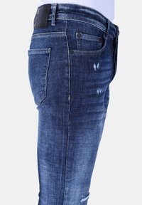 Donkerblauwe denim jeans met een slim fit, voorzien van verwerkte details, vijf zakken en een leren label op de taille.