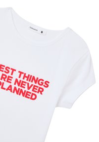 Maglietta in cotone bianco a maniche corte, con scritta in grassetto rossa che recita "LE COSE MIGLIORI NON SONO MAI PIANIFICATE." Girocollo standard.