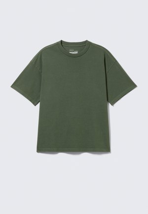 Απλό βαμβακερό κοντομάνικο t-shirt σε ελιά πράσινο χρώμα με στρογγυλή λαιμόκοψη, το οποίο απεικονίζεται επίπεδο πάνω σε ανοιχτό γκρι φόντο.
