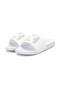 Sandalias deslizantes blancas con una textura suave, presentando un logo geométrico beige en la correa y una suela plana y flexible.
