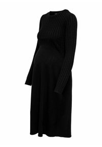 Robe de maternité noire en tricot avec une texture côtelée, des manches longues, un col rond et un bustier ajusté, s'élargissant en une jupe ample.