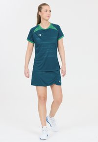 Teal sportkläder bestående av en kortärmad topp med gröna detaljer och en matchande kjol, med FZ-logotyp på båda plagg.