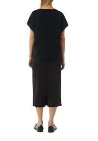 Czarny bawełniany t-shirt o luźnym kroju, krótki rękaw i okrągły dekolt, zestawiony z czarną spódnicą o średniej długości z tylnym rozcięciem.