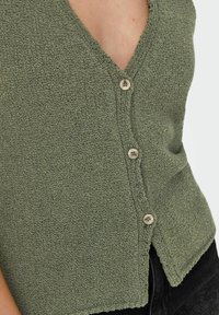 Cardigan verde a trama con scollo a V e cinque bottoni. Presenta un morbido tessuto lavorato a maglia e un orlo leggermente incrociato.