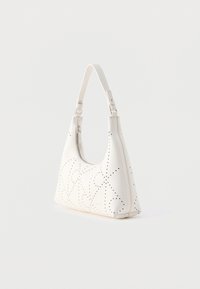 Άσπρη δερμάτινη τσάντα ώμου με διάτρητα γεωμετρικά σχέδια και λεπτομέρεια με ασημένιο φερμουάρ, τοποθετημένη σε απλό ανοιχτό φόντο.