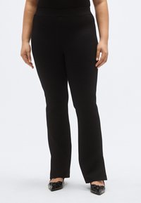 Mustad laia säärega püksid, millel on sile ja veniv kangas ning lai vöökoht. Disain on ilma nähtavate taskute või kaunistusteta.