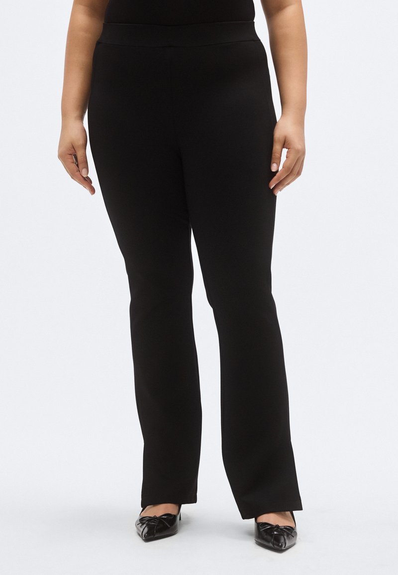 Mustad laia säärega püksid, millel on sile ja veniv kangas ning lai vöökoht. Disain on ilma nähtavate taskute või kaunistusteta.