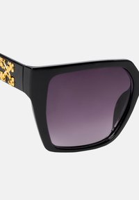 Czarne, oversize okulary przeciwsłoneczne o geometrycznej konstrukcji. Gradientowe ciemnofioletowe soczewki oraz złote akcenty na zausznikach. Smukły i nowoczesny design.