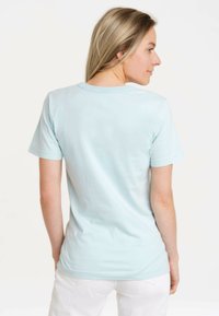 Helles blaues Baumwoll-T-Shirt mit kurzen Ärmeln, Rundhalsausschnitt und taillierter Form, von hinten vor einem weißen Hintergrund präsentiert.