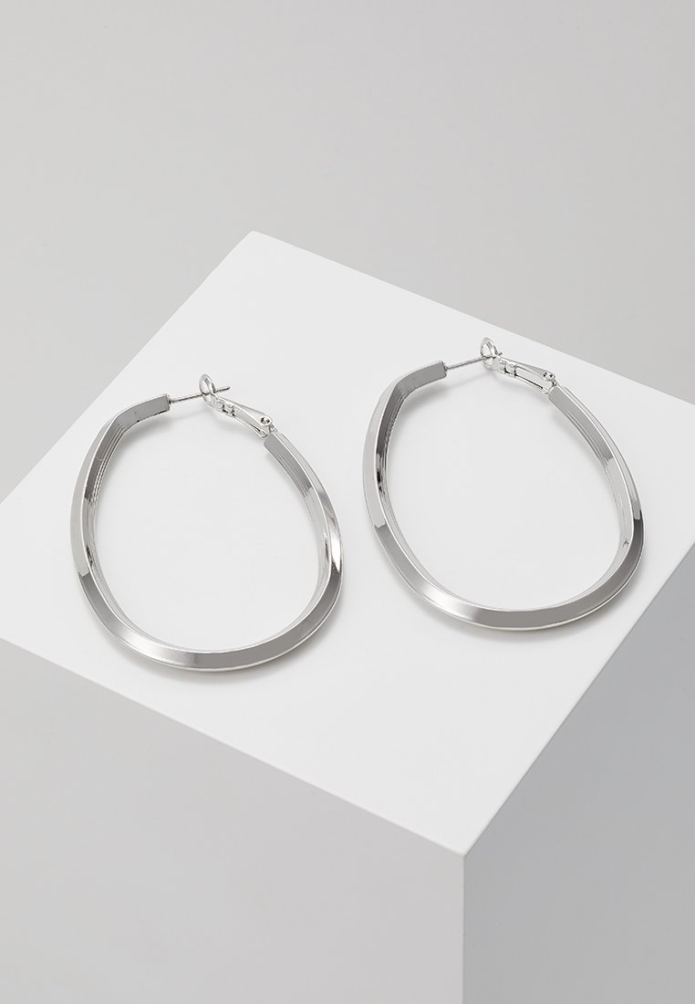 Sidabriniai auskarai žiedais, su glotnia ovalia forma ir lygiu paviršiumi. Turi hinged užsegimą, užtikrinantį saugų dėvėjimą.