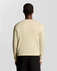 Πουλόβερ με μακριά μανίκια σε ανοιχτό μπεζ πλεκτό ύφασμα, με στρογγυλή λαιμόκοψη και ριμπ μανσέτες, συνδυασμένο με μαύρο παντελόνι. Λείο υλικό, μινιμαλιστικός σχεδιασμός.