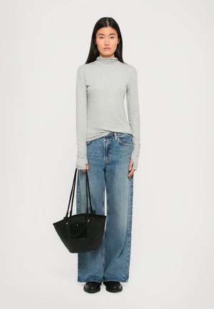Gray long-sleeve top with a high collar, light blue wide-leg jeans, and a black textured tote bag. Solid colors throughout.