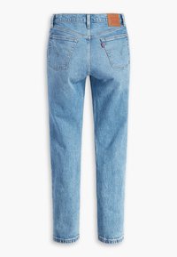 Jean en denim bleu vu de dos avec deux poches arrière, une étiquette de marque en cuir sur la ceinture et une étiquette de marque rouge sur la poche droite.