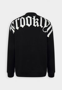 Felpa nera con maniche lunghe e polsini a coste, con grande testo bianco "CROOKLYN" sul retro in un font stilizzato.
