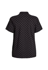 Camisa polo negra de manga corta, con un patrón de lunares blancos, cuello y un corte relajado. Tejido suave con una textura sutil.