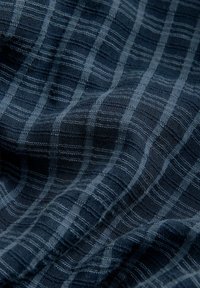 Marineblauwe stof met een gestructureerd geruit patroon, met afwisselend lichte en donkere strepen die een geblokt ontwerp creëren.