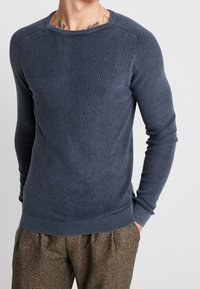 Maglione a costine blu navy con maniche lunghe e scollatura a girocollo, caratterizzato da una finitura textured e un silhouette aderente.