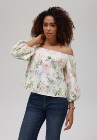 Avskåret bluse med blomsterdesign i lett stoff, med pastellfargede blomster, puffede ermer og en avslappet passform, kombinert med mørk denim.