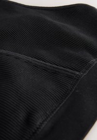 Tessuto nero strutturato con una fine costina e un dettaglio di cucitura dritta. Il materiale appare morbido e flessibile, adatto all'abbigliamento.