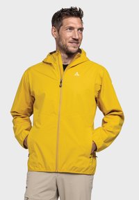 Gelbe wasserdichte Jacke mit durchgehendem Reißverschluss, verstellbarem Kapuzen und elastischen Bündchen. Verfügt über ein Logo auf der linken Brust und seitliche Taschen.