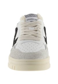 Sneaker in pelle bianca con dettagli in suede nera, finiture grigie testurizzate sulla suola e lacci beige. Presenta un colletto imbottito e la punta perforata.