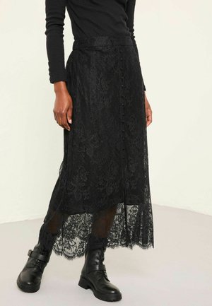 Black lace maxi skirt with a button front, featuring a floral pattern and sheer hem, paired with black combat boots.