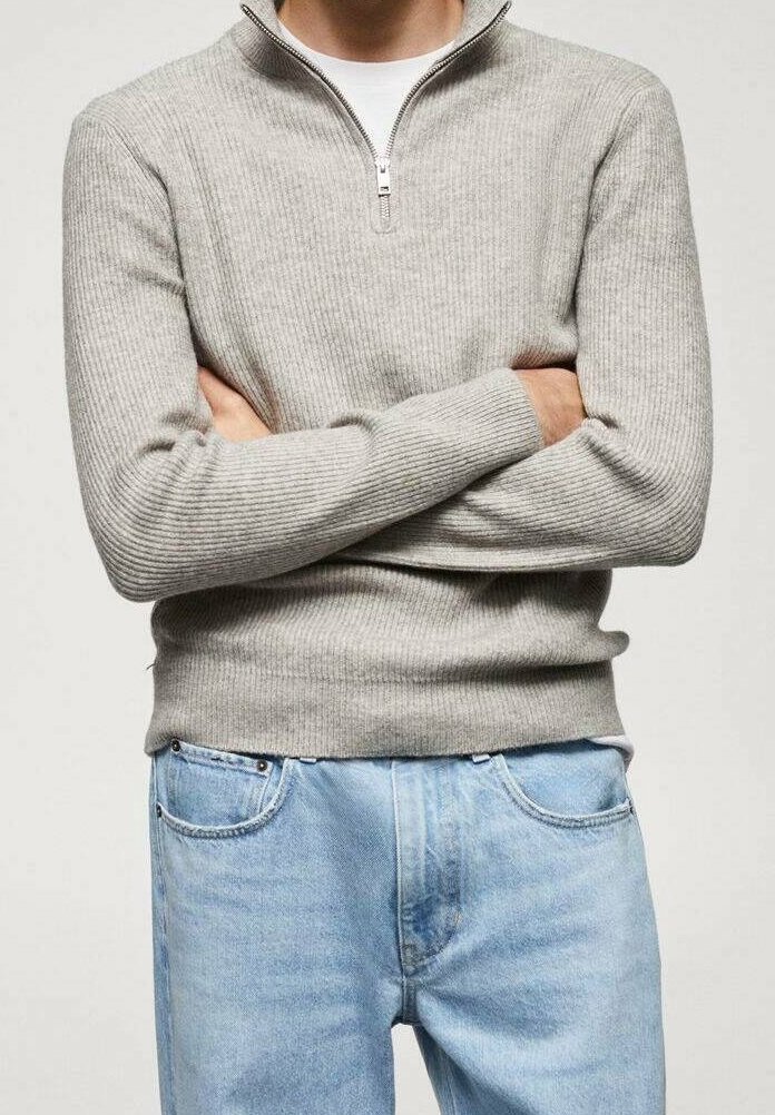 Světle šedý žebrovaný pletený svetr s polo zipem, zkombinovaný se světle modrými džíny. Nastavitelný zip a strukturovaný materiál.