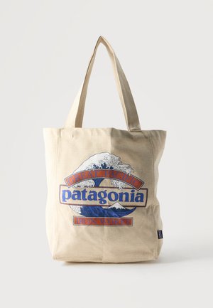 Beige lærreds-tote-taske med blå bølge- og bjergdesign, med teksten "Great Pacific Patagonia Iron Works."