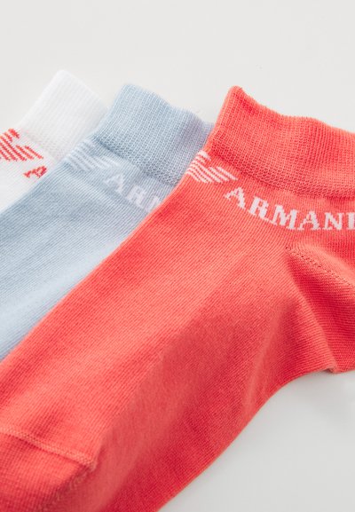 Trois paires de chaussettes courtes : blanches avec des accents rouges, bleu clair et corail. Chacune est fabriquée en maille lisse et comporte un logo sur le poignet.