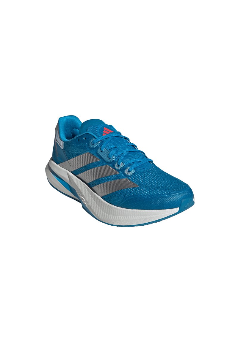 Blue athletic shoe with a textured mesh upper, silver stripes, and a white midsole. Features round laces and a padded collar.