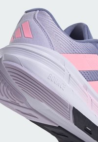 Botte de sport violette avec des accents roses. Tige en tissu texturé, semelle lisse et détail "BOUNCE" sur la semelle intermédiaire. Design profil bas.