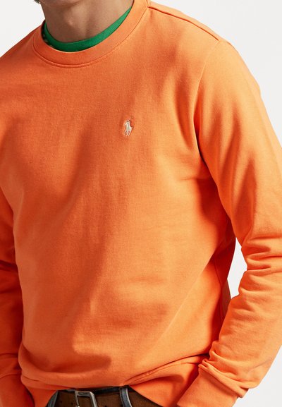 Orange long-sleeve sweatshirt with a crew neck and ribbed cuffs, featuring a small white embroidered logo on the chest.