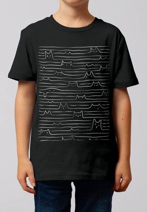 Kind draagt zwart T-shirt met witte doorlopende lijntekening van meerdere kattengezichten en poten, gerangschikt in horizontale rijen.