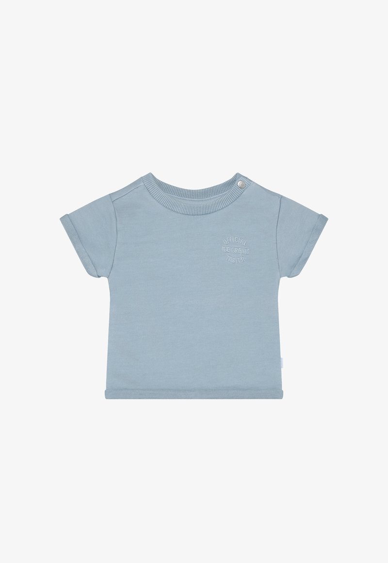 T-shirt à manches courtes bleu clair en tissu doux. Présente un col rond avec des pressions et un détail en texte embossé à l'avant.