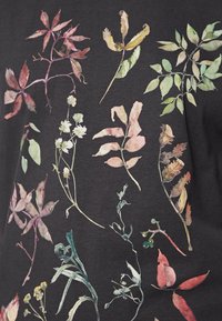 Černá tkanina s akvarelovým květinovým potiskem, s listy v odstínech zelené, růžové a fialové, ukazujícími podrobné textury a tvary.