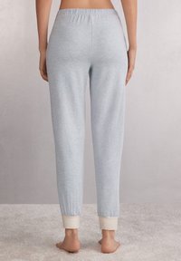 Lichtblauwe, zachte katoenen joggers met een elastische tailleband en crèmekleurige boorden. Losse pasvorm met minimale details, gladde textuur.