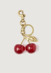 Χρυσό μεταλλικό μπρελόκ με δύο λαμπερές κόκκινες ποικιλίες κερασιού και ένα φύλλο σε λευκό φόντο.