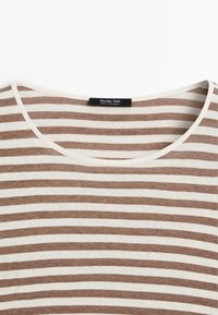 Gestreiftes Kurzarmoberteil mit hellbraunen und cremefarbenen horizontalen Streifen, weichem Stoff und rundem Ausschnitt mit sichtbar angebrachten Etikett.