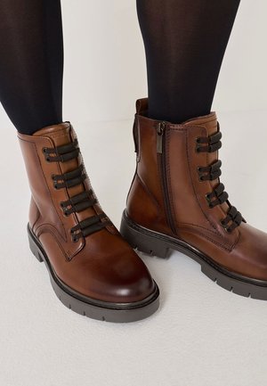 Braune Leder-Ankle-Boots mit Schnürung und Reißverschluss, strukturiertem Obermaterial, runder Zehenpartie und einer massiven schwarzen Gummisohle.