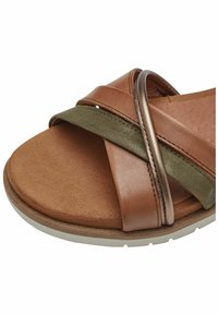 Sandalo in pelle marrone con cinturini verde oliva e bronzo metallizzato. Presenta una suola piatta e morbida con un plantare strutturato e forma arrotondata.