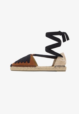 Sandalia espadrille con parte delantera de ante marrón, tacón beige tejido, suela trenzada de yute y largas tiras negras para atar al tobillo.