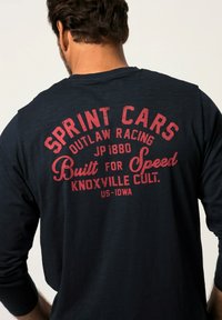 Camisa de manga larga navy con texto rojo: "SPRINT CARS OUTLAW RACING JP1880 Construida para velocidad KNOXVILLE CULT. US-Iowa", con una textura suave.