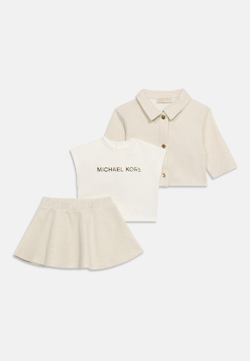 Παιδικ ή μπεζ φούστα με γκλίτερ, ταιριαστό σακάκι με μισά μανίκια και γιακά με χρυσά κουμπιά, και λευκή αμάνικη μπλούζα με το λογότυπο «Michael Kors».