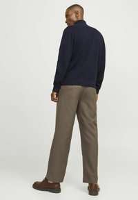 Pulover navy cu guler înalt, asortat cu pantaloni largi maro și pantofi maro. Puloverul are un finisaj texturat și o croială lejeră.