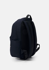 Zaino blu navy con tessuto liscio, schienale in rete, spallacci regolabili e tasca laterale. Presenta un design semplice e lineare con cuciture rinforzate.