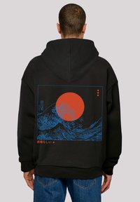 Sudadera negra con un gráfico de ola azul y un sol rojo, acentuada con texto japonés. Material suave, diseño de talla grande, costuras visibles a lo largo de los bordes.