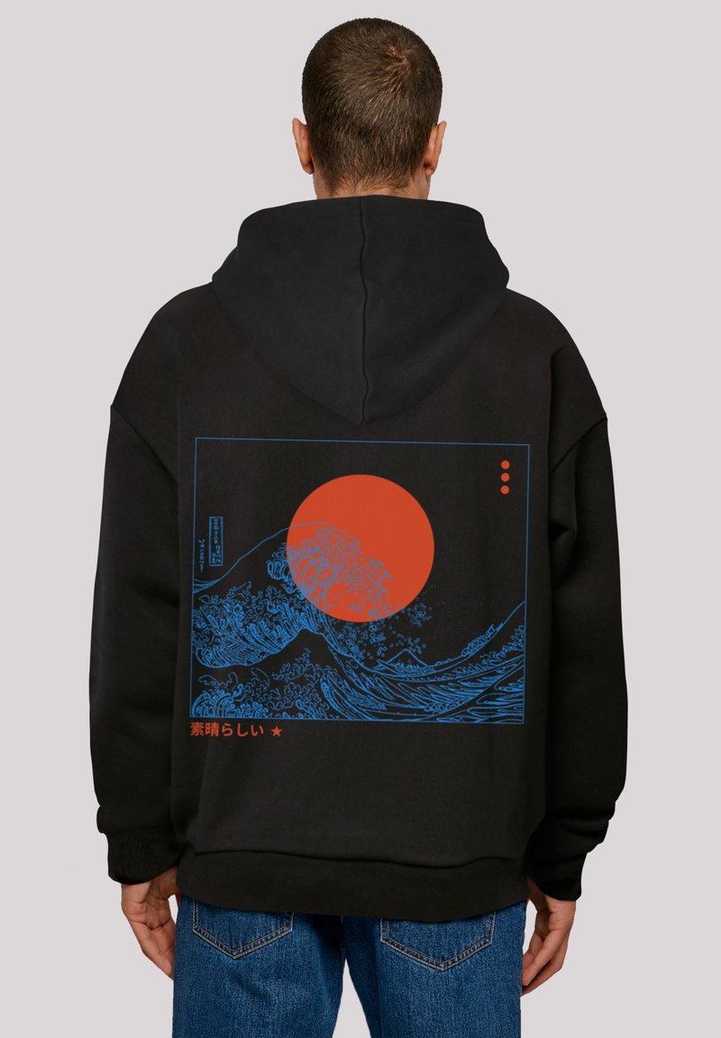 Sudadera negra con un gráfico de ola azul y un sol rojo, acentuada con texto japonés. Material suave, diseño de talla grande, costuras visibles a lo largo de los bordes.