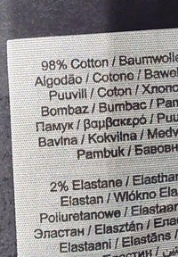 Etykieta pokazująca skład tkaniny: 98% bawełna, 2% elastan, nadrukowana w wielu językach na teksturowanym, jasnym tle tkaniny.